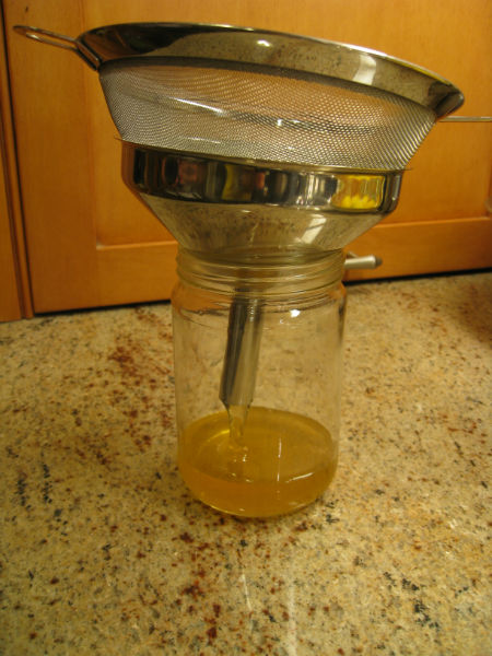 Using a fine sieve and a funnel to get the honey into a jar.