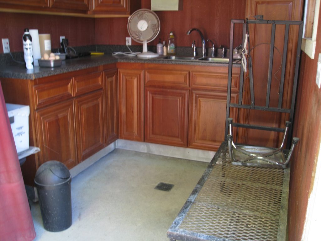 Goats step up onto the metal frame for milking. The outdoor kitchen stores supplies and allows for cleanup.